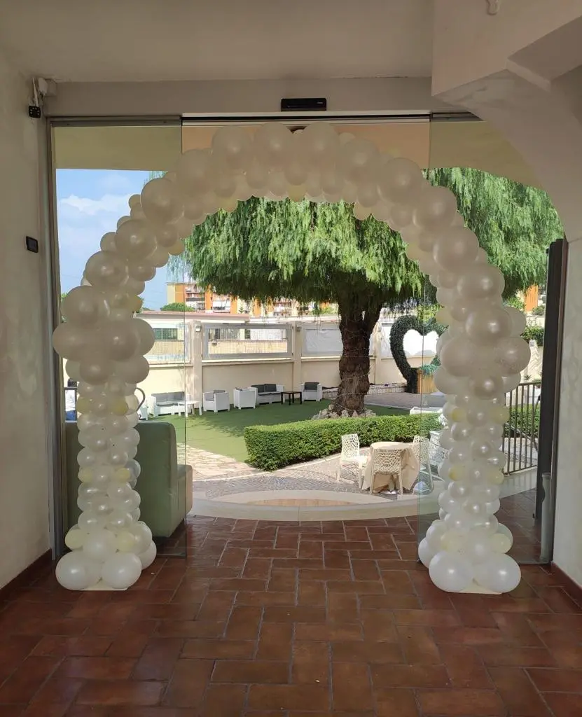 Arco di palloncini bianchi all'ingresso della sala affacciata sul giardino