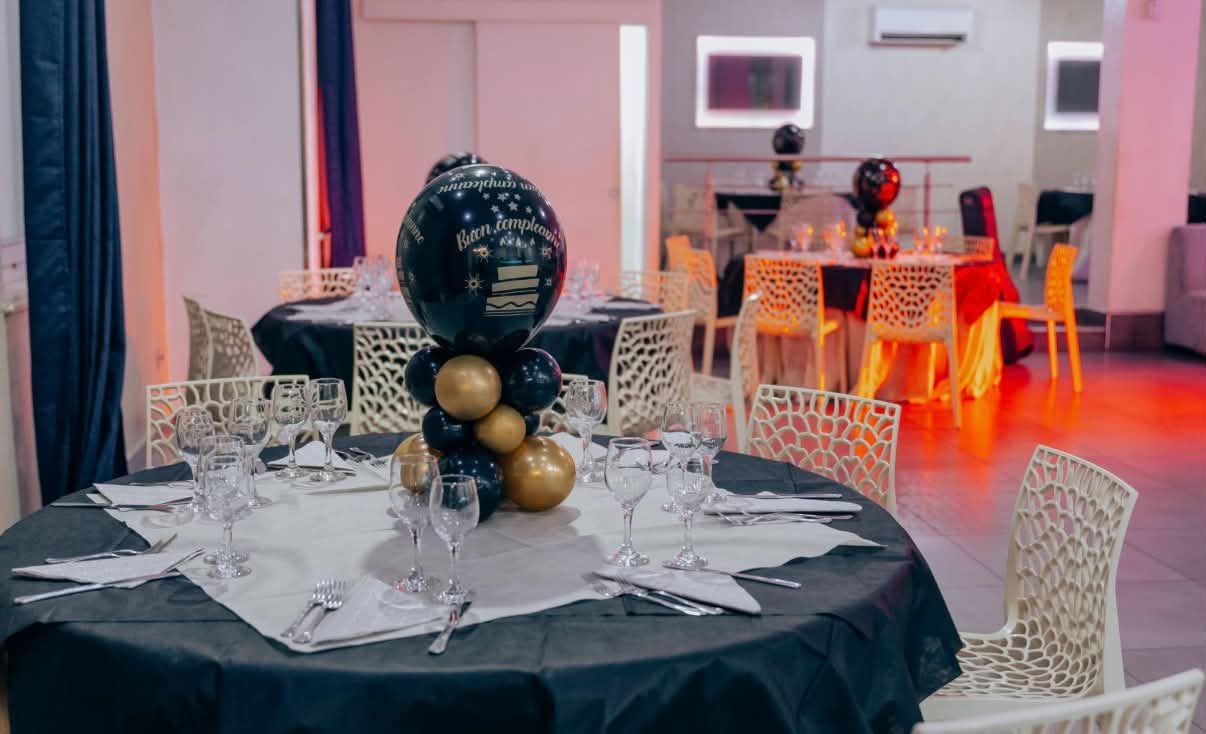 Sala interna allestita con tavolo nero e centrotavola di palloncini Buon compleanno