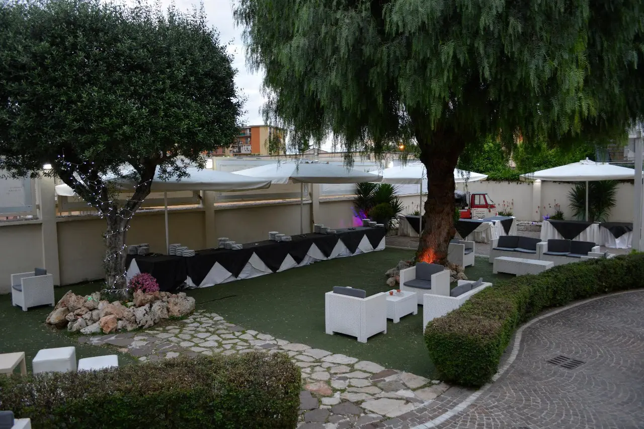 Giardino lounge della villa con divanetti bianchi, alberi illuminati e buffet