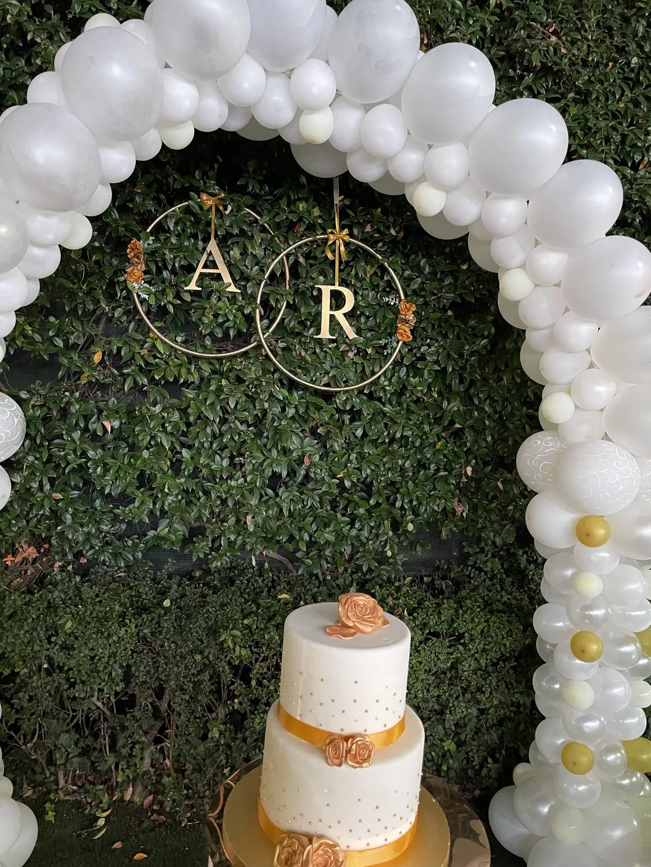Arco di palloncini bianchi e oro con torta a due piani decorata con rose dorate